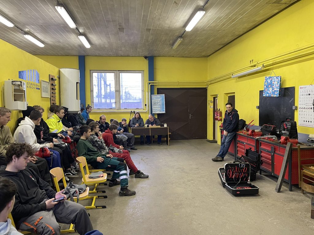 Zámečnická dílna, kde na levé straně sedí studenti oboru instalatér a před nimi stojí přednášející obchodník ze společnosti Knipex.