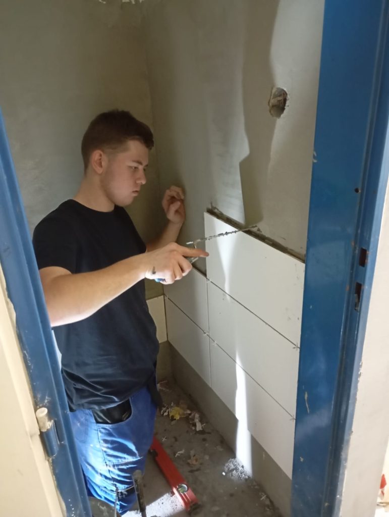 Žák obkládá stěnu obkladačkami