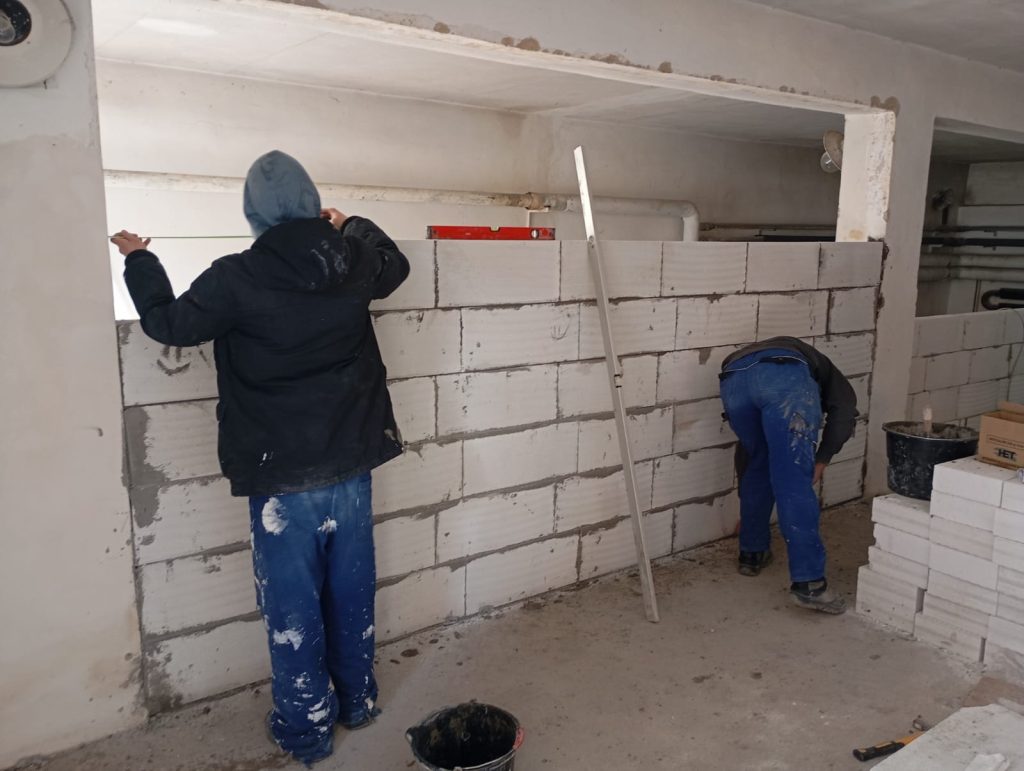 Žáci oboru zedník pracují u zdi