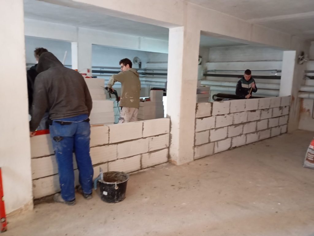 Žáci oboru zedník pracují u zdi