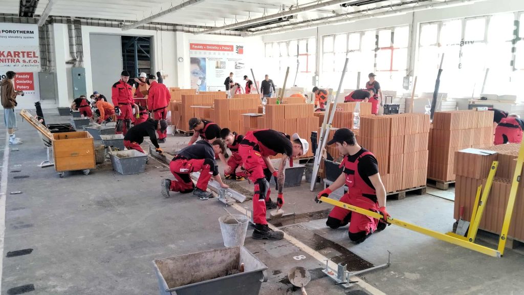 Na fotografii jsou žáci v dílně odborného výcviku při soutěži, kde provádějí zdění z různých stavebních materiálů.