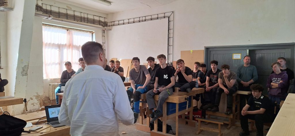 Odborník přednáší žákům před projekčním plátnem