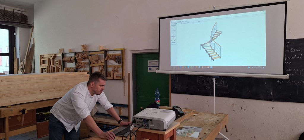 Odborník přednáší žákům před projekčním plátnem na kterém jsou schody