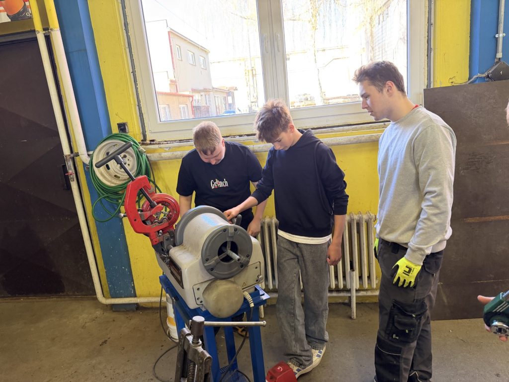 Třída naslouchá žákům 1. ročníku kteří jim předvádějí elektrický závitořez.